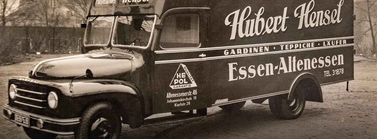 Alter Lieferwagen mit Aufschrift Polstermöbel Hubert Hensel und Essen Altenessen steht auf Straße vor Gebäuden